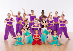 All levels of Acro Dance Class posed in their purple, teal, and red, dance recital costumes